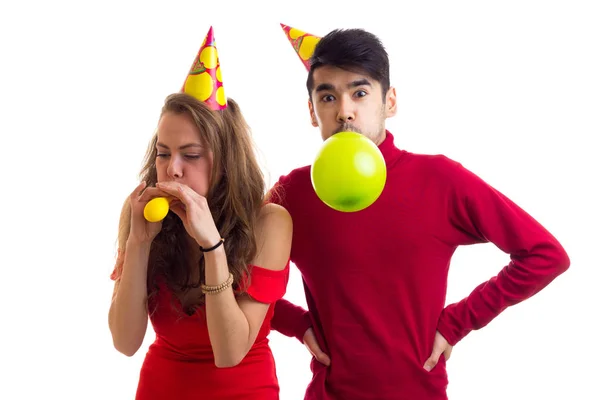 Joven pareja soplando globos — Foto de Stock