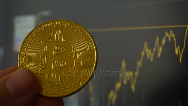 Wachsende Bitcoin-Münze in den Händen von Mann gegenüber Handelsterminal — Stockvideo