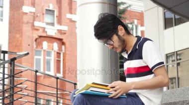 Merdivenlerde oturan ve kitap okuma adam Asya öğrenci portresi