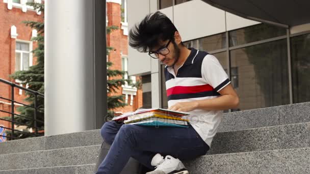 Человек азиатский студент сидит на лестнице и читает книгу — стоковое видео