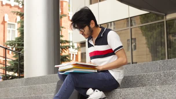 Adulte mâle asiatique étudiant assis sur escaliers et lecture livre — Video
