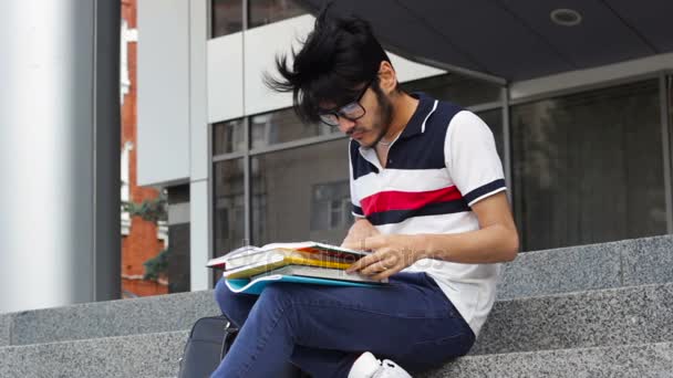 Азиатский студент сидит на лестнице и читает книги — стоковое видео