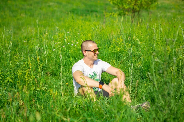 Man sitting in the grass in sunglasses — Stock Photo, Image