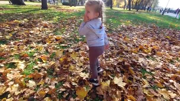 Маленька дівчинка втікає і тремтить в осінньому парку — стокове відео