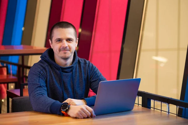 Mann im Kapuzenpulli mit Laptop sitzt am Schreibtisch — Stockfoto