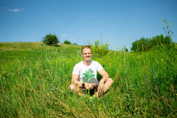 Man freelancer sitting on grass with laptop — Stock Photo, Image