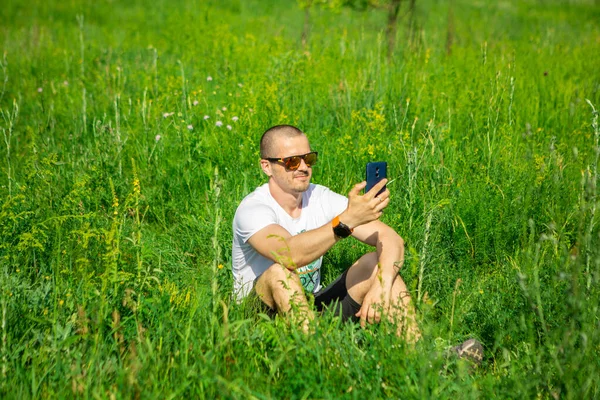 El hombre con smartphone y gafas de sol sonríe — Foto de Stock