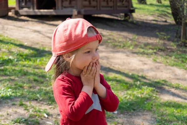 Menina surpreendida em boné vermelho olhando para alguém — Fotografia de Stock