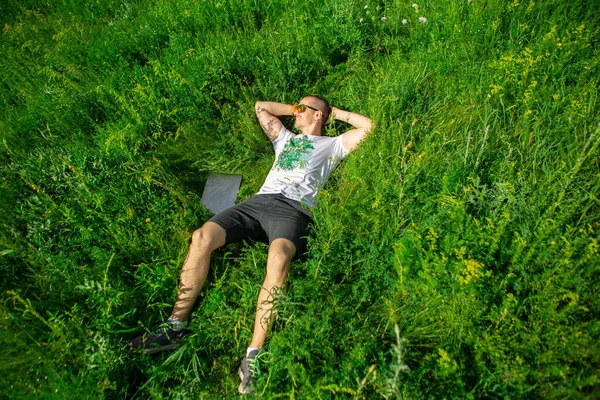 Freelancer en el trabajo tumbado en la hierba en el prado con portátil —  Fotos de Stock