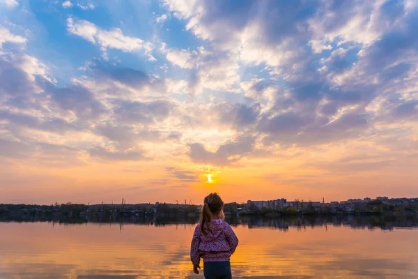 Kislány áll vissza a kamerába, és nézi a naplementét — Stock Fotó