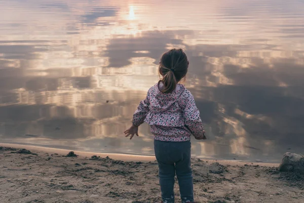 Маленькая девочка смотрит на отражение заката — стоковое фото