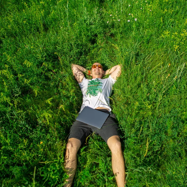 Vista superior del hombre acostado en la hierba con el ordenador portátil —  Fotos de Stock