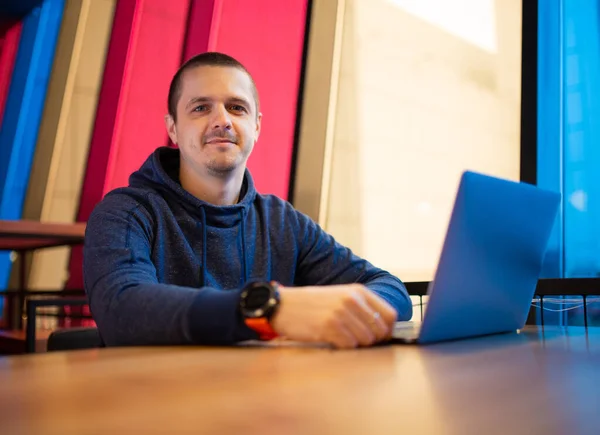 Człowiek freelancer na biurku z laptopem patrząc w aparacie — Zdjęcie stockowe