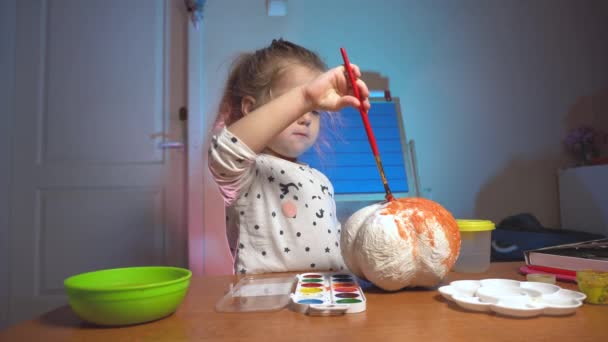 Kleines Mädchen färbt gefälschtes Handwerk in orangefarbener Farbe — Stockvideo