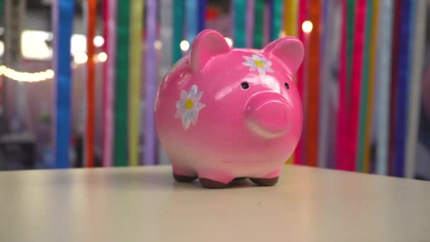 Pink porcelain pig moneybox with flowers standing on desk — Stock Video