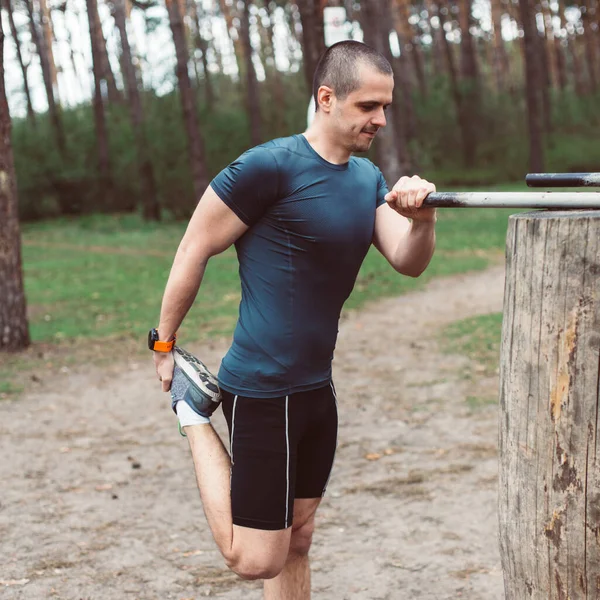 Człowiek robi rozciąganie po poranku bieganie w lesie — Zdjęcie stockowe
