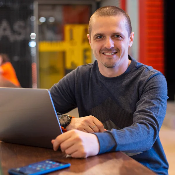 Mann mit Laptop blickt in Kamera und lächelt — Stockfoto