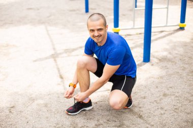 Erkek adam antrenmandan önce ayakkabısına ayakkabı bağı bağlar.