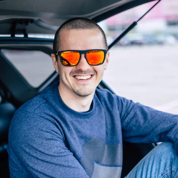 Man in orange sunglasses smiling and looking in camera