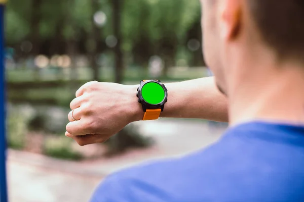 Hombre mirando su reloj inteligente con pantalla cromakey verde —  Fotos de Stock