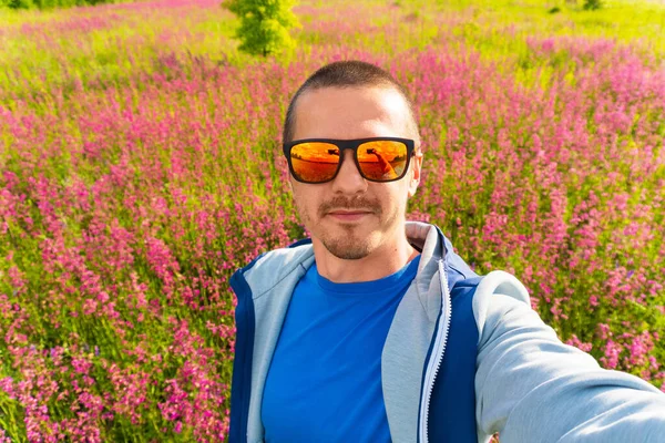 Людина в кольорових сонцезахисних окулярах робить селфі стоячи в полі — стокове фото