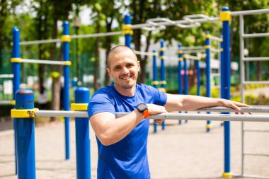 Spor salonunda sporcu kameraya bakıyor ve gülümsüyor.