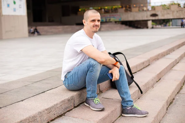 Man zittend op de trap in het park met rugzak achter zich — Stockfoto