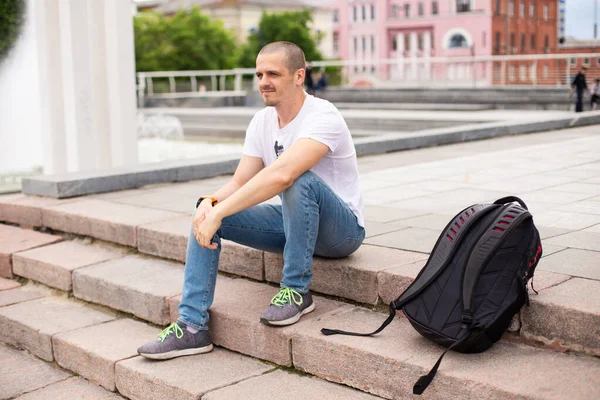 Hombre viajero sentado en las escaleras y relajarse en el parque urbano —  Fotos de Stock