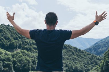 Mutlu adam kameraların önünde dağ vadisine bakıyor.