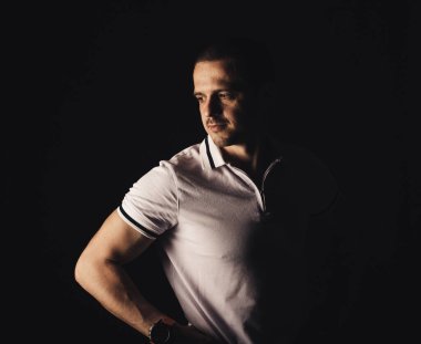 Stüdyoda beyaz tişörtlü bir adam var.