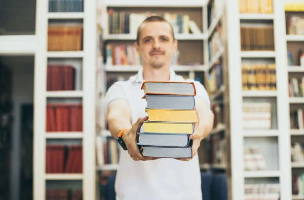 Zaměřeno na knihy v rukou člověka v moderní knihovně — Stock fotografie