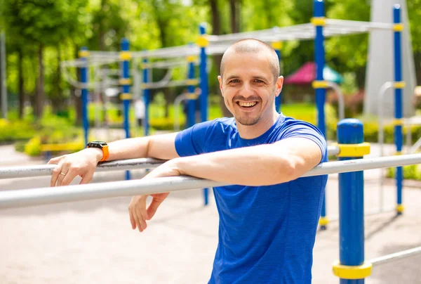 Muž sportovec se usmívá a dívá se do kamery opírající se o mříže — Stock fotografie