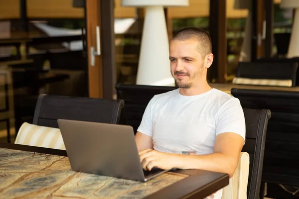 Дорослий чоловік сидить в ресторані або кафе і працює на ноутбуці — стокове фото
