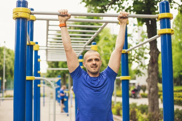 Człowiek robi pull up ćwiczenia w parku — Zdjęcie stockowe