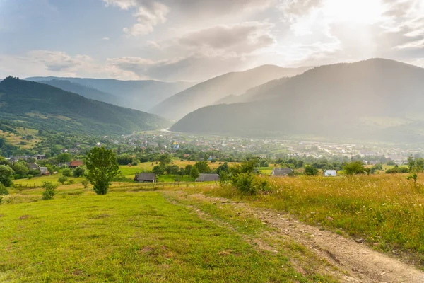 Fantastisk utsikt över dalen med byn mellan bergen under sommarregn — Stockfoto