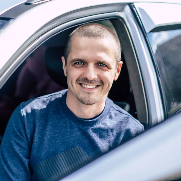 Sorrindo homem olhando na câmera através da janela do carro — Fotografia de Stock