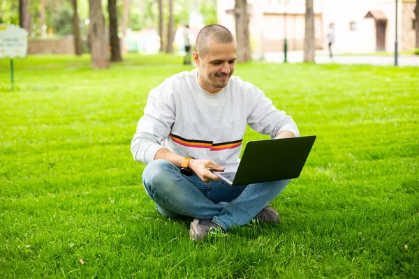 Człowiek freelancer deweloper pracuje na laptopie siedzi na trawniku — Zdjęcie stockowe