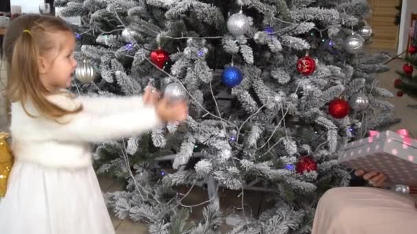 ママはクリスマスツリーと彼女の小さな女の子にギフトボックスを与える — ストック動画