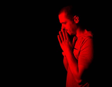 Kırmızı ışıkta dua eden adam stüdyoda duruyor.