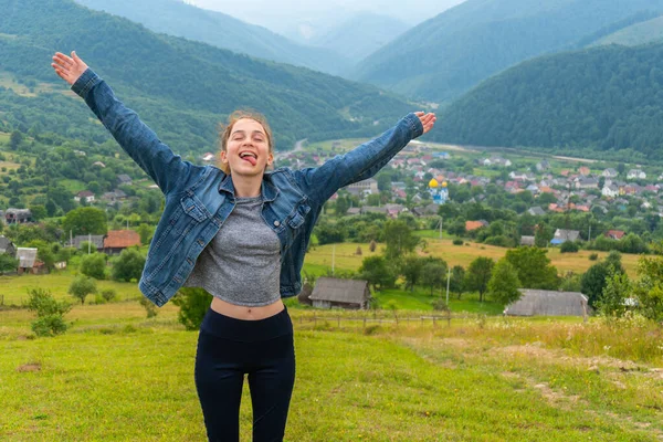 Komik ve mutlu genç kız dağların arkasında zirvede duruyor. — Stok fotoğraf