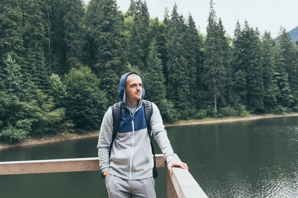 Hombre viajero mirando lejos de pie al aire libre cerca de lago de montaña —  Fotos de Stock