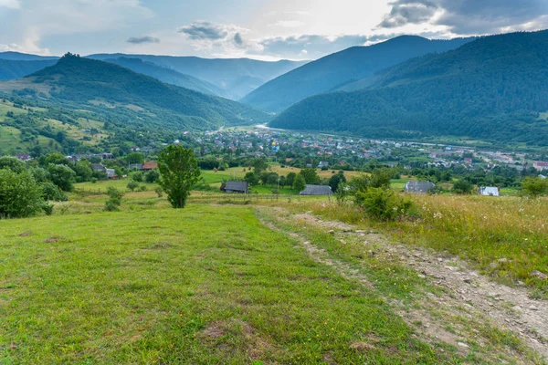 Vista rurale sulla valle con piccolo viallage e grandi montagne — Foto Stock