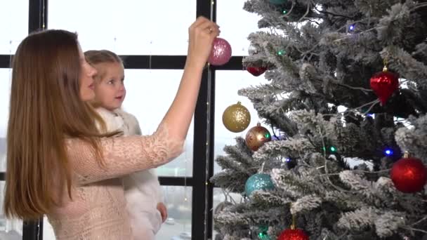 Vrouw mam en daighter klein meisje versieren kerstboom met speelgoed — Stockvideo