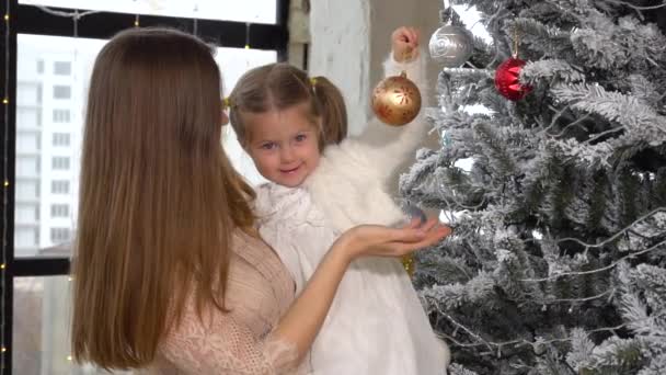 Moeder houden haar kind meisje op handen en ze spelen met kerst speelgoed — Stockvideo