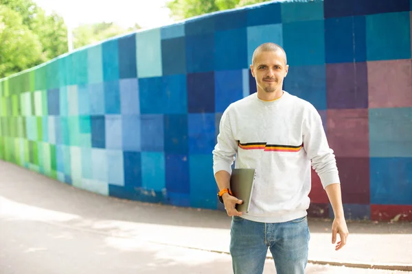 Uomo con computer portatile in piedi nel parco estivo — Foto Stock