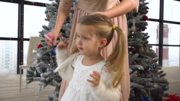 Mamá haciendo peinado a niña con árbol de Navidad detrás — Vídeos de Stock