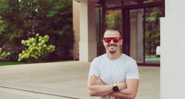 Mannen i solglasögon tittar in i kameran och ler — Stockfoto
