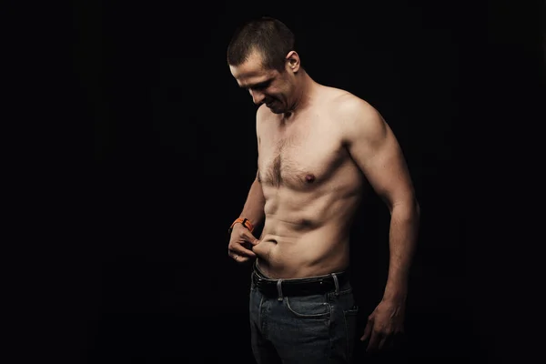 Мужчина трогает свой жир на груди стоя в студии — стоковое фото