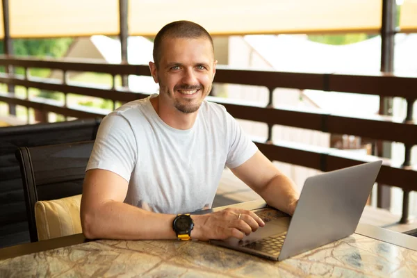 Glimlachende man freelancer kijken in de camera en werken op laptop. — Stockfoto
