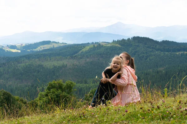 Женщина и девочка веселятся на холме с горами позади — стоковое фото